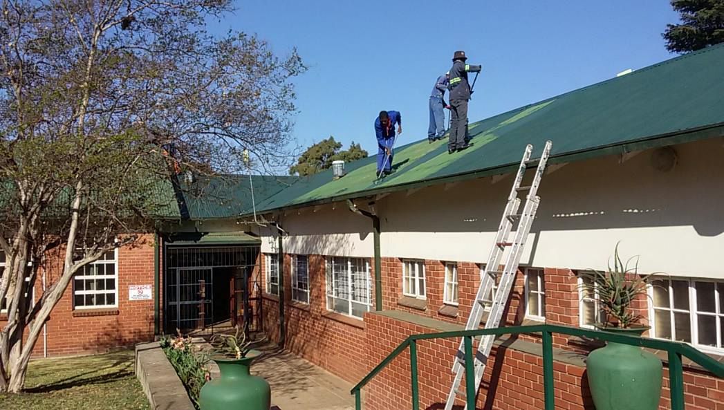 Contractors painting the roof of Aloe Ridge School