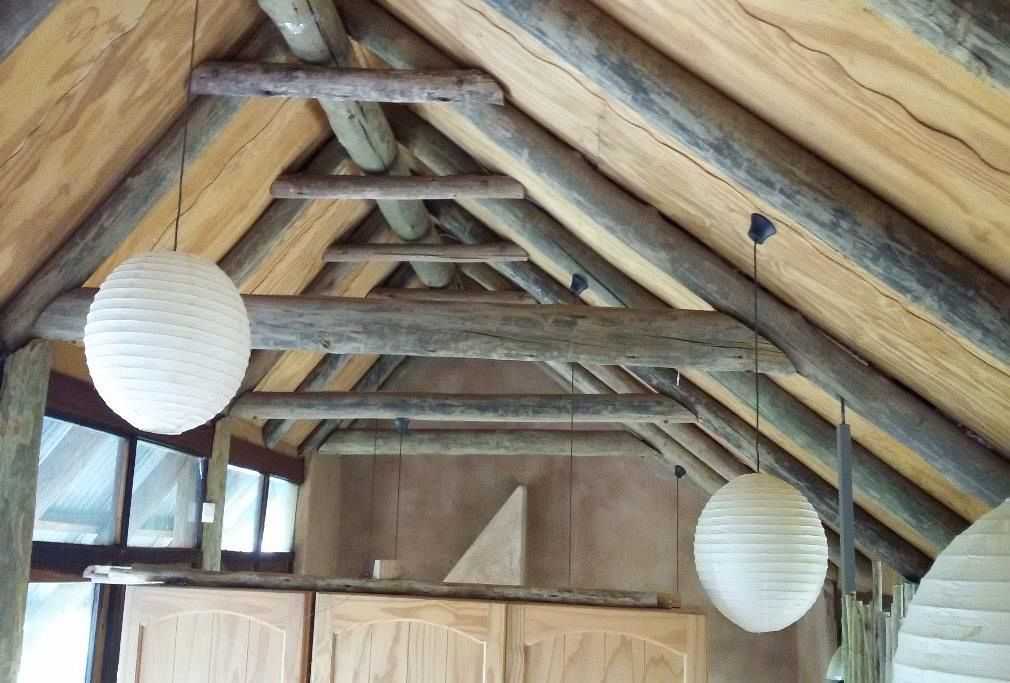 Plywood ceiling installed beneath an exposed-timber thatch roof